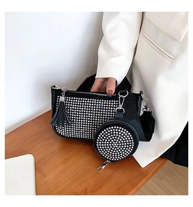 Detail of a black rhinestone underarm bag with a round coin purse and silver tassels
