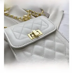 Close-up of white quilted leather bag with gold twist lock and chain strap detail