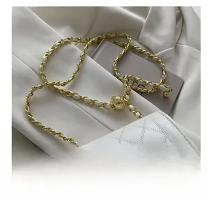 Detail of white quilted leather texture with gold-tone ball chain adjuster and twist lock