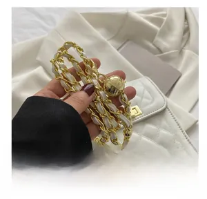 Detail of white quilted handbag with gold metal and leather woven chain strap