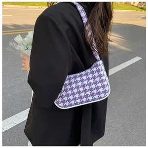 Detailopname van paarse houndstooth schoudertas van tweed op de schouder van het model