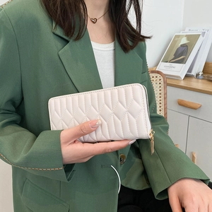 Women's cream quilted long wallet with gold zipper, elegant clutch held by model