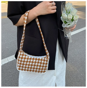 Bruine houndstooth baguette tas gedragen door model met witte tulpen