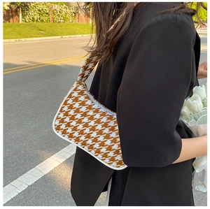 Detail van de bruine houndstooth schoudertas textuur vastgehouden met tulpen
