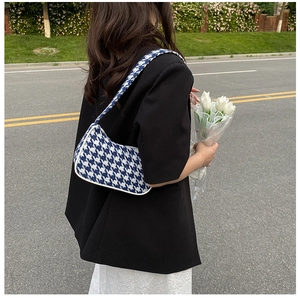 Blauwe houndstooth okseltas gestyled met model in straatbeeld en witte tulpen