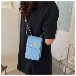 Detail of light blue quilted phone bag with gold chain strap and elegant turn-lock