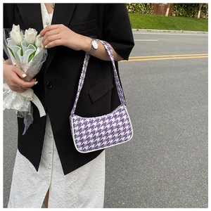 Paarse houndstooth onderarmtas gestyled met een professionele zwarte blazer outfit
