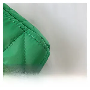Close-up of premium green quilted fabric with cross-stitch patterns on a small square bag
