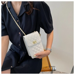 White quilted crossbody bag with gold chain strap worn by a model in a black dress