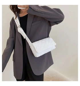 Detailed view of white quilted crossbody bag with adjustable wide shoulder strap on model