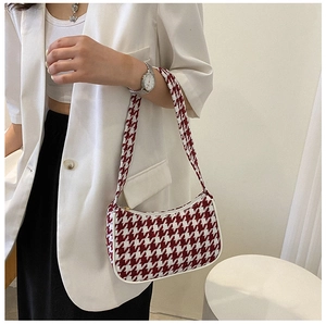 Detail van rood-wit pied-de-poule patroon en ritsrand op de trendy baguette tas