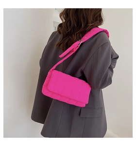 Close-up of bright pink quilted shoulder bag with metal buckle and nylon fabric detail