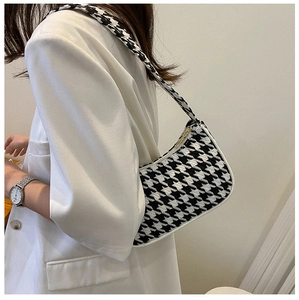 Detailopname van de houndstooth-onderarmtas met witte lederen bies op een model