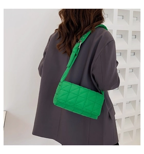 Detailed back view of a quilted lime green puffer crossbody bag on a grey suit jacket