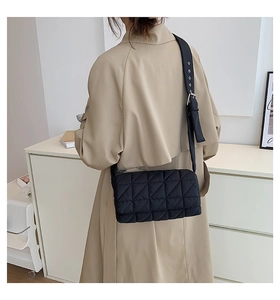 Detail of black quilted shoulder bag featuring premium puffy texture and metal buckle strap