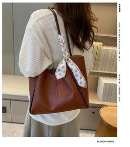Detail of large brown tote bag featuring a decorative silk scarf and smooth PU leather