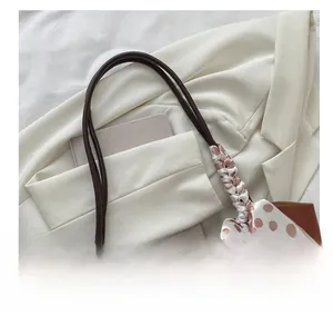 Close-up of brown leather tote bag with silk scarf detail on the handle for office style