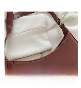 Detail view of smooth dark brown leather texture with fine stitching and silver buckle