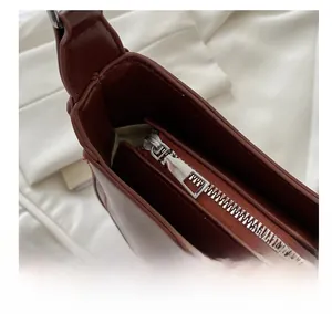 Macro detail of the smooth silver zipper closure on a vintage dark brown shoulder bag