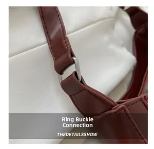 Detail of silver metal ring buckle connecting deep red leather strap and bag
