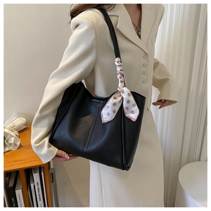 Close-up of black PU leather tote bag with polka dot silk scarf on shoulder strap