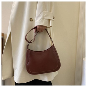 Detail of a vintage dark brown crescent bag worn with a white trench coat in lifestyle scene