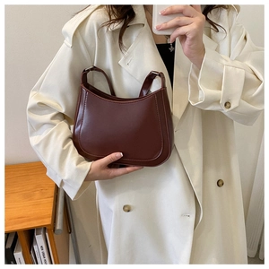 Model wearing dark reddish-brown vintage hobo shoulder bag with a beige trench coat