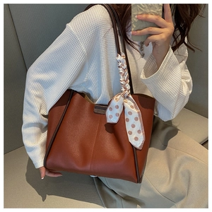 Close-up of caramel tote bag featuring lychee texture and decorative polka dot silk scarf