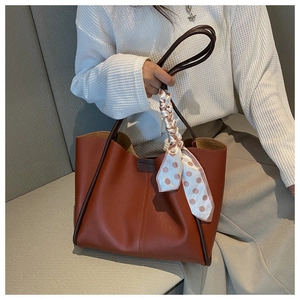 Detail of red-brown tote bag with a polka dot silk scarf and slim brown handle