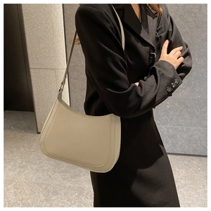 Close-up of cream leather baguette bag with fine stitching on model in black suit