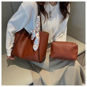 Detail view of brown leather tote bag with silk scarf accent and matching inner pouch