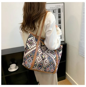 Ethnic style woven tote bag with geometric patterns and brown leather handles detail