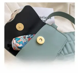 Close-up of mint green pleated crossbody bag with gold magnetic snap and diamond texture