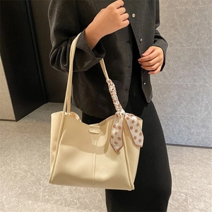 Cream leather tote bag with elegant silk scarf detail and slim shoulder straps on model