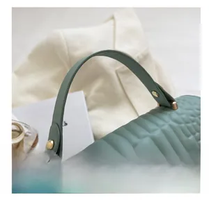 Detail of crocodile embossed grey leather handbag with golden rivets and arc handle