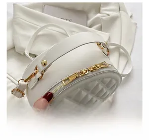 Close-up of golden metal zipper and quilted rhombus texture on white crossbody bag