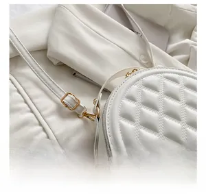 Detail of white quilted handbag featuring gold-tone hardware hooks and stitching