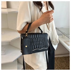 Detailed view of black crocodile pattern handbag with gold hardware and mini pouch