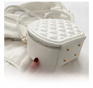 Detail of white quilted handbag showing silver zipper and golden protective bottom studs