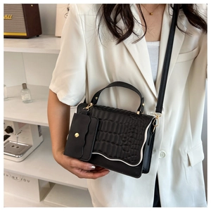 Close-up of black crocodile texture handbag with wave-edge flap and small pouch