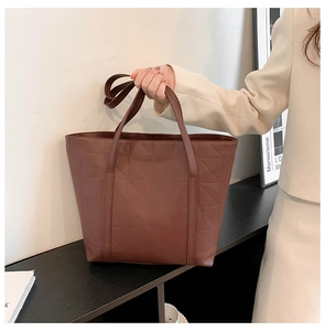 Detail of dark brown tote bag with triangle quilted texture and sturdy top handles