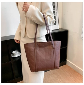 Detail of coffee brown quilted tote bag showing geometric triangle texture and long straps