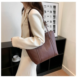 Brown quilted tote bag on model shoulder with elegant white suit for office commuters
