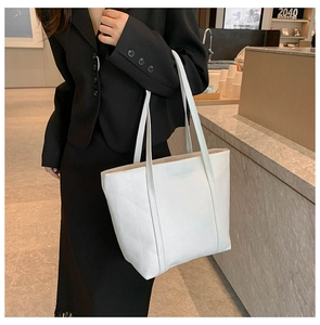 Close-up of white quilted PU leather tote bag on model in black suit for work office