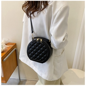 Close-up of quilted pattern on black circular shoulder bag with gold zipper details