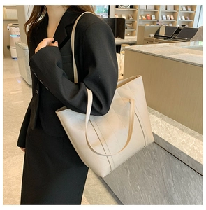 Detail of elegant beige quilted tote bag with diamond pattern on black blazer