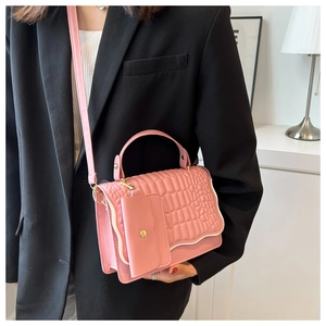 Pink crocodile-embossed handbag with wavy flap and detachable coin purse on black suit