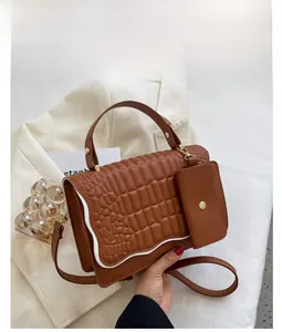 Detail of brown embossed leather handbag with gold hardware and detachable mini pouch