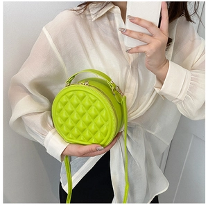 Detail of neon green round quilted crossbody bag with rhombic stitching and dual zippers
