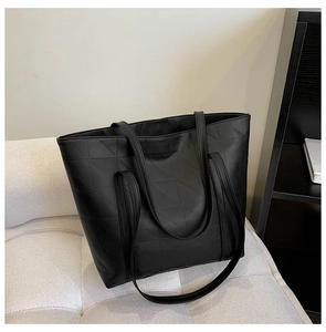 Detail of black quilted tote bag with geometric triangle patterns and long handles